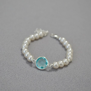 Close-up of pearl beaded bracelet featuring light blue faceted crystal and silver clasp