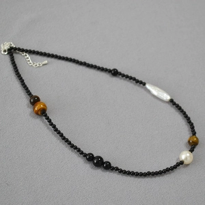 Detail of beaded necklace with black onyx, tiger eye stones, and baroque pearls