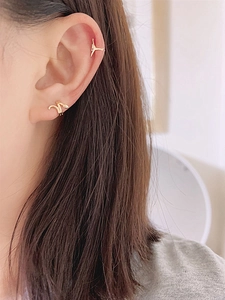 Detailed close-up of delicate gold snake-shaped brass cuff earrings worn on the ear
