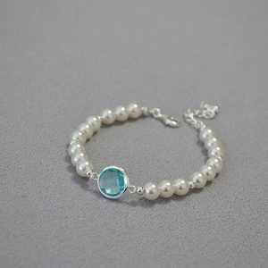 Detailed shot of pearl bracelet with light blue crystal centerpiece and lobster clasp