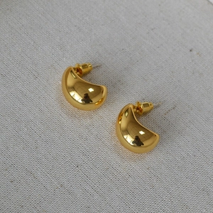 Detailed view of polished gold water drop earrings with a reflective metallic finish