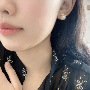 Vue détaillée des boucles d'oreilles en perles et barre dorée portée par un modèle