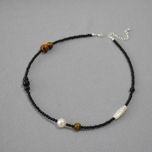 Close-up of beaded necklace featuring black onyx, tiger eye stones, and freshwater pearls