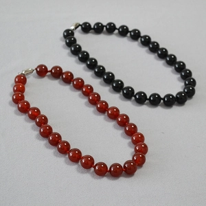 Detail of red agate and black onyx beaded necklaces with glossy finish and silver clasps