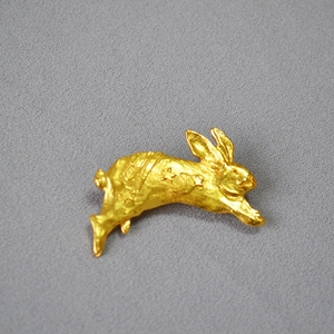 Macro detail of gold rabbit brooch featuring hammered texture and star moon engravings