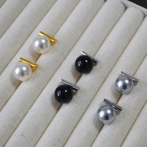 Trois paires de boucles d'oreilles en perles blanche, noire et grise sur plateau