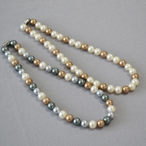 Detail of round pearl necklaces in vintage bronze and ivory tones with metallic clasps