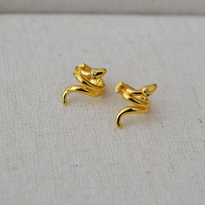 Detailed close-up of gold snake earrings featuring sparkling white zircon accents