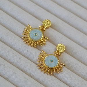 Retro brass sunburst earrings with natural turquoise stones on beige jewelry tray