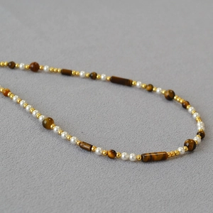 Detail of tiger eye beads and pearls on retro asymmetric necklace with gold accents