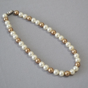 Detail of two-tone white and champagne gold round pearl necklace with metal clasp
