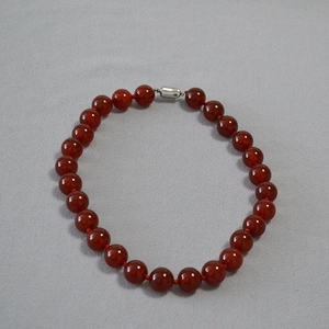 Detail of red agate beaded necklace showing glossy round stones and silver buckle
