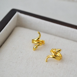 Elegant gold-plated brass snake hoop earrings with rhinestone eyes on linen tray