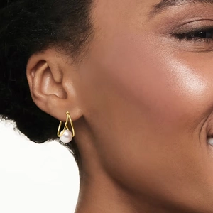 Detailed view of hollow teardrop gold earrings with round white pearl on model ears
