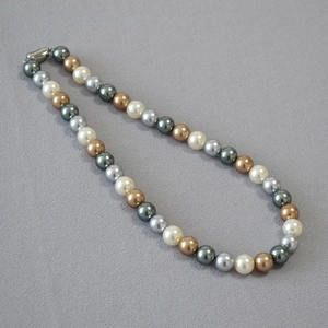 Detail view of multi-color pearls necklace with round white gold and green pearls