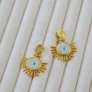 Detail of vintage gold sunburst earrings with turquoise stone and textured brass finish