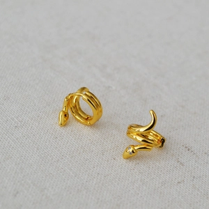 Macro shot of gold-plated brass snake hoop earrings with zircon-embedded eyes