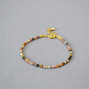 Detailed macro view of colorful square stone beads and golden spacers on a slim bracelet