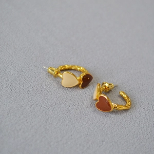 Detail of vintage heart enamel hoop earrings with irregular gold-plated texture