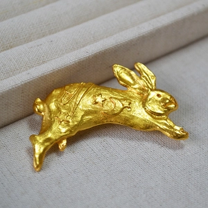 Macro view of running rabbit brooch with vintage textured gold finish and star engraving