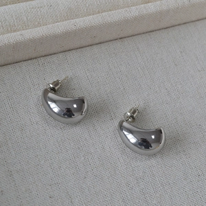 Polished silver bean teardrop earrings in a minimalist design on textured fabric