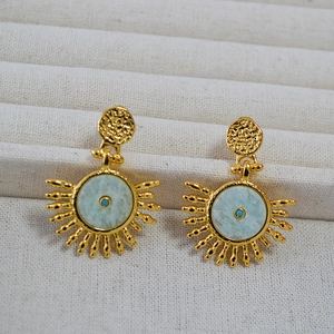 Detail of sunburst earrings with hammered brass texture and green stone inlay