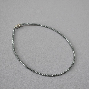 Macro shot of dark grey pearl bead necklace with a polished silver bean shaped clasp