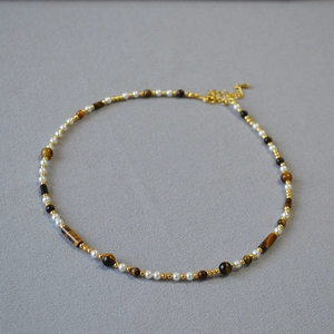 Close-up of vintage beaded necklace with tiger eye stones, pearls and lobster clasp