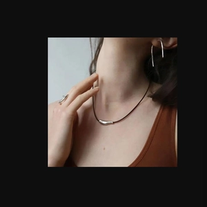 Close-up of minimalist silver abstract pendant necklace and jewelry set on model