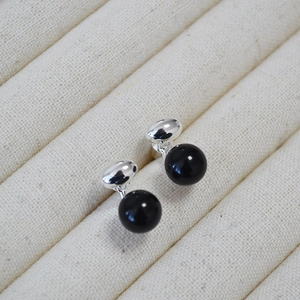Elegant 925 sterling silver stud earrings with round black onyx stones on beige tray