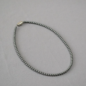 Detailed shot of dark grey pearl necklace featuring a polished silver magnetic clasp