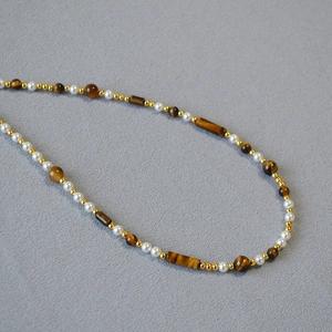 Macro detail of tiger eye beads and pearls on an asymmetric vintage necklace