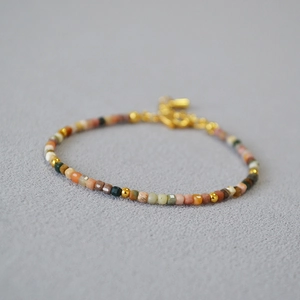 Macro shot of earthy-toned square beads and gold spacers on a minimalist beaded bracelet