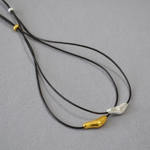 Minimalist brass abstract bird pendant on black leather cord with gold and silver finish