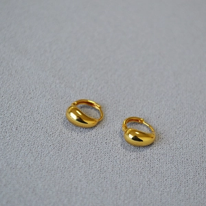 Detailed close-up of minimalist gold-plated teardrop earrings with a polished finish