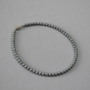Close-up of deep grey pearl necklace featuring a silver heart-shaped toggle clasp
