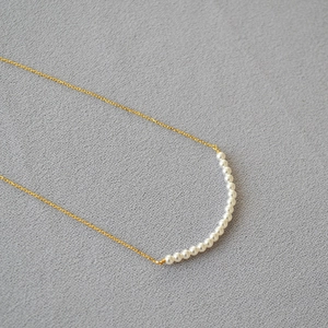 Macro detail of seventeen round pearls on a delicate gold chain for elegant daily wear