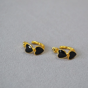 Detail shot of double black enamel heart earrings with elegant gold plated finish