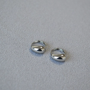 Polished silver teardrop earrings on grey knit fabric, minimalist fashion jewelry