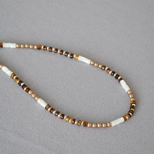 Collier bohème avec pierres œil de tigre et perles en nacre sur tissu gris