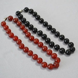 Detail view of red and black agate beaded necklaces with silver ingot clasps