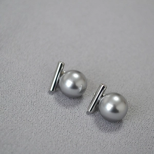Détail de la boucle d'oreille barre argentée avec perle grise sur tissu texturé
