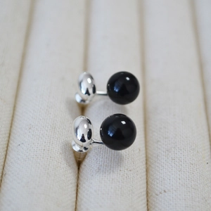 Minimalist silver 925 stud earrings with black onyx beads on light textured background