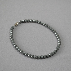 Elegant French style grey pearl necklace with a smooth metallic clasp on grey fabric