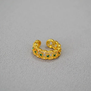 Detailed macro view of gold-plated lace ring with green and white zircon stones
