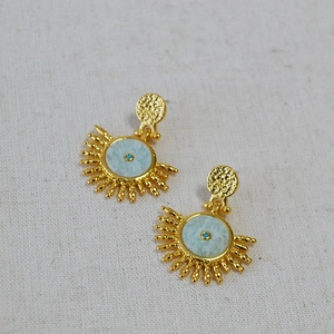 Vintage sunburst brass earrings with turquoise blue stones on beige textured fabric