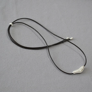 Macro view of adjustable leather cord necklace with polished silver abstract bird pendant