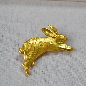 Macro view of matte gold rabbit brooch featuring celestial moon and star engravings