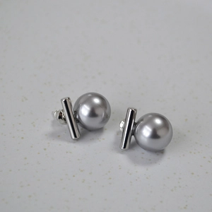 Détail de boucles d'oreilles barre en argent avec perles grises sur fond texturé