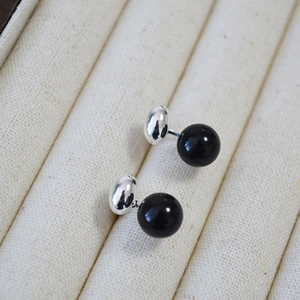 Macro shot of minimalist black agate stud earrings with silver base in a jewelry box
